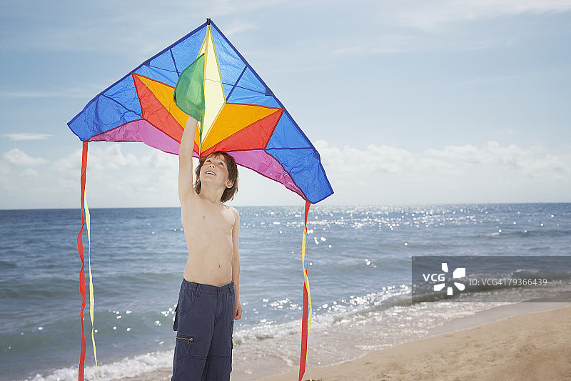 一个小男孩在海滩上拿着风筝图片素材