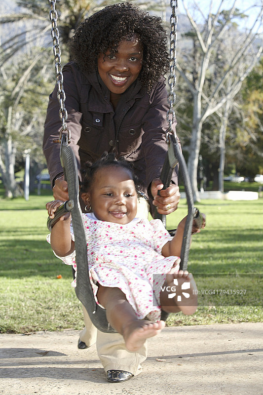 母亲在公园里让女儿荡秋千。德瓦尔公园，开普敦，西开普省，南非图片素材