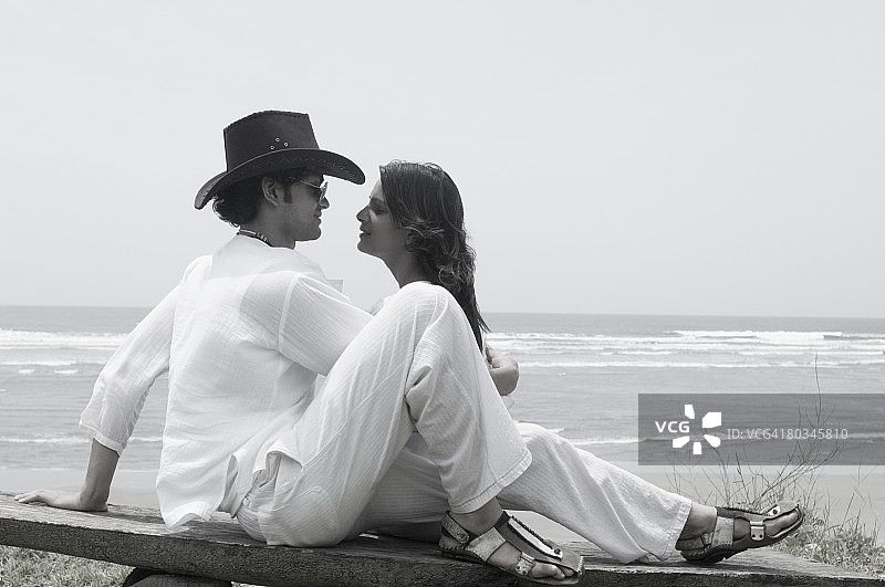 一对年轻夫妇坐在海滩上图片素材