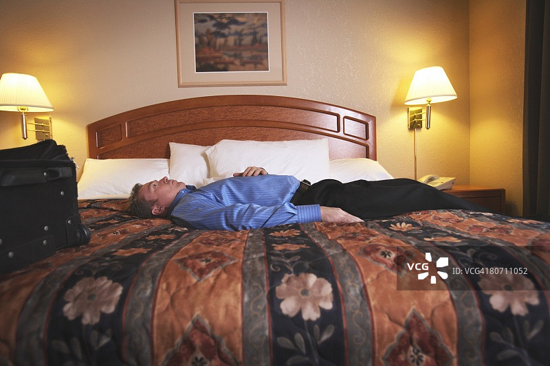 一个男人躺在酒店房间的床上图片素材