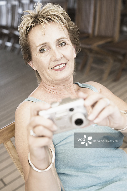 一个成熟女人拿着数码相机微笑的肖像图片素材