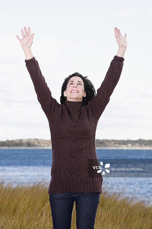 成熟的女人高举双臂站在沙滩上图片素材