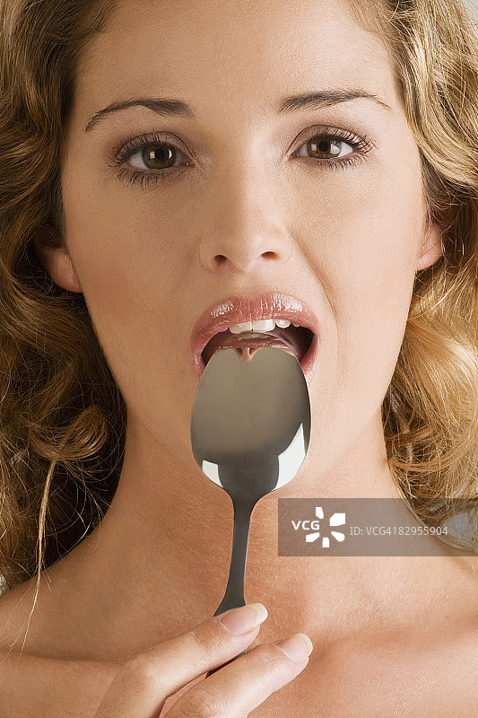一个嘴里含着勺子的年轻女人的肖像图片素材