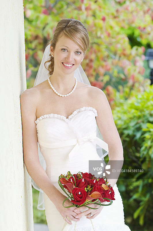 新娘靠墙微笑。图片素材