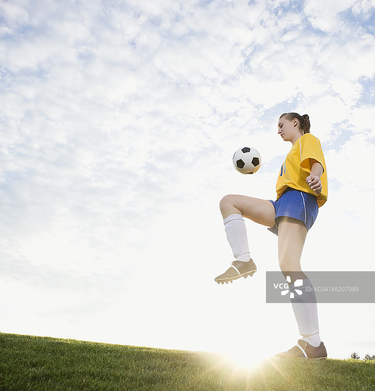 十几岁的女孩在膝盖上踢足球图片素材