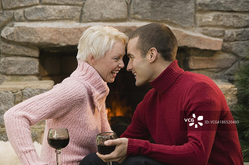 一对夫妇在壁炉旁放着酒杯图片素材