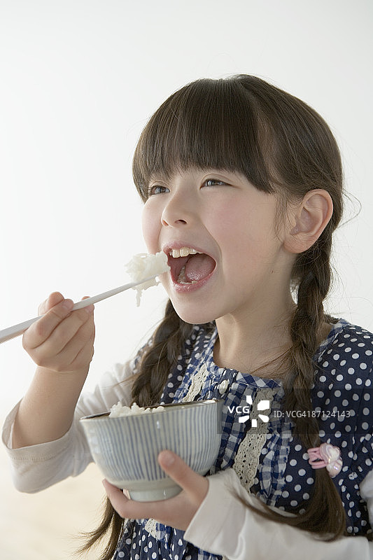 女孩(8-9)用筷子吃米饭图片素材