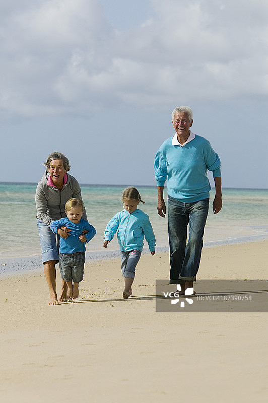 一对成熟的夫妇和他们的孙子在海滩上散步图片素材