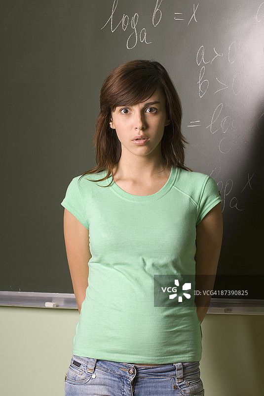困惑的女学生站在黑板前的肖像图片素材