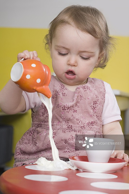 小女孩把牛奶洒在桌子上图片素材
