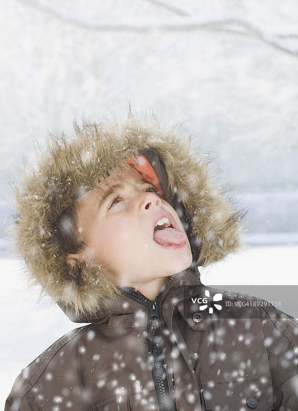 男孩在雪中伸出舌头图片素材