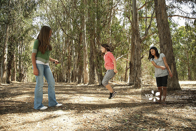 三个女孩在森林里跳绳图片素材