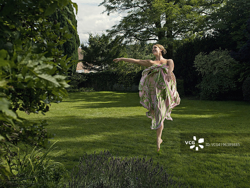 一个年轻女子在花园里跳舞图片素材
