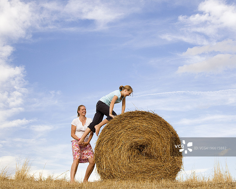 女人帮助女孩爬干草堆图片素材