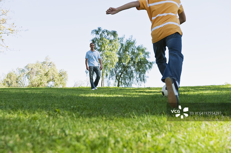 爸爸和儿子在公园踢足球图片素材