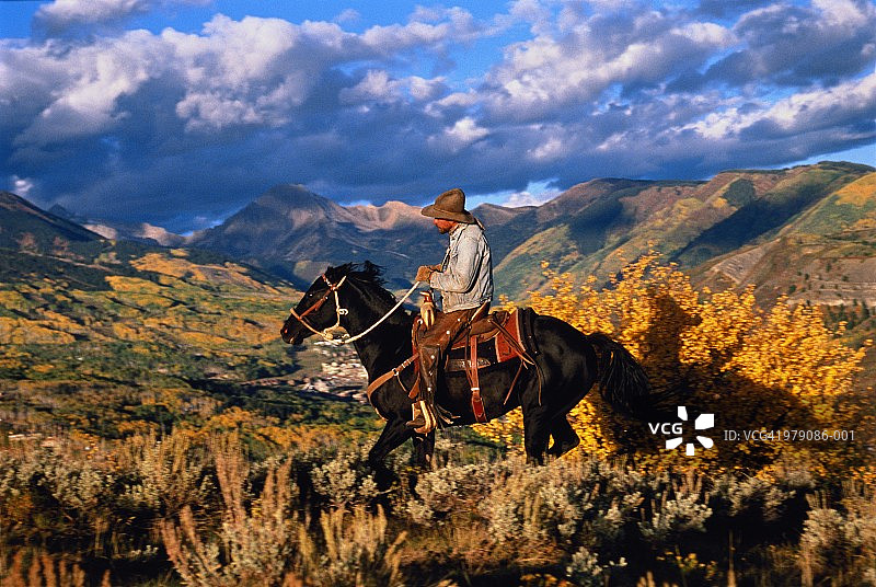 美国科罗拉多州，斯诺马斯，牛仔骑在小镇上方的山脊上图片素材