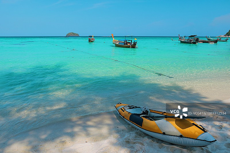 风景欣赏皮划艇和长尾船在海滩上对着天空，泰国图片素材