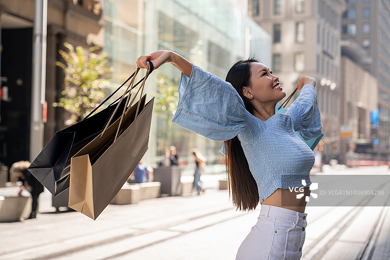 美丽的亚洲购物女人看起来很高兴在户外图片素材