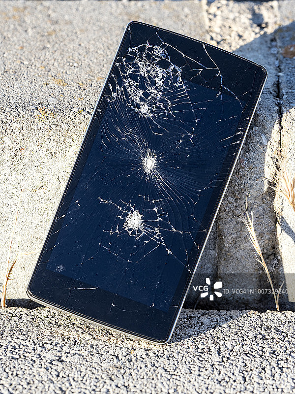 手机碎玻璃被丢弃在街道的地板上。图片素材
