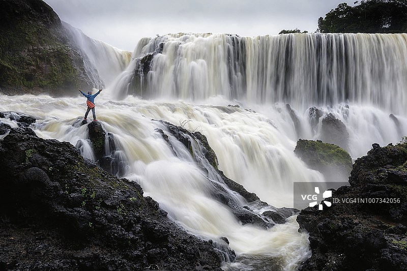 一个冒险站在强大的瀑布图片素材