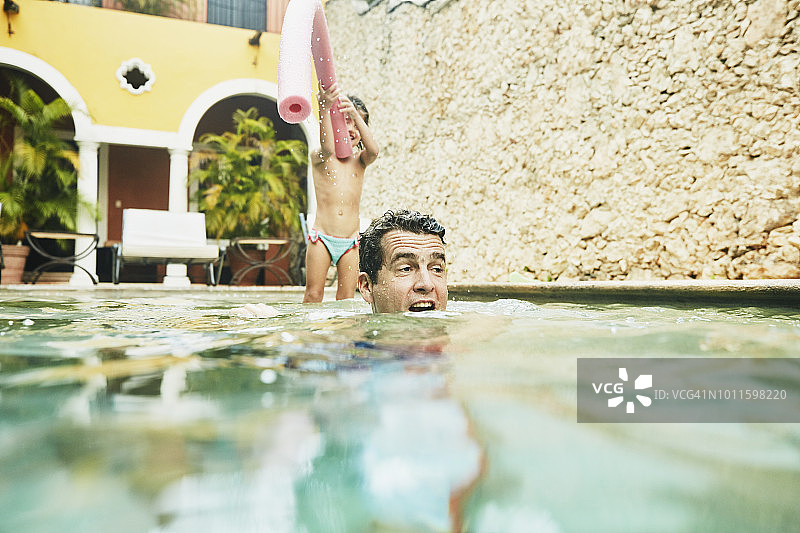 爸爸和女儿在热带度假村的游泳池里玩图片素材