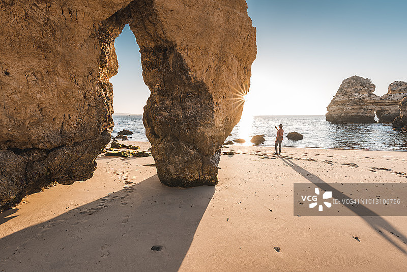 葡萄牙阿尔加维，日出时分，一名男子站在海滩上图片素材
