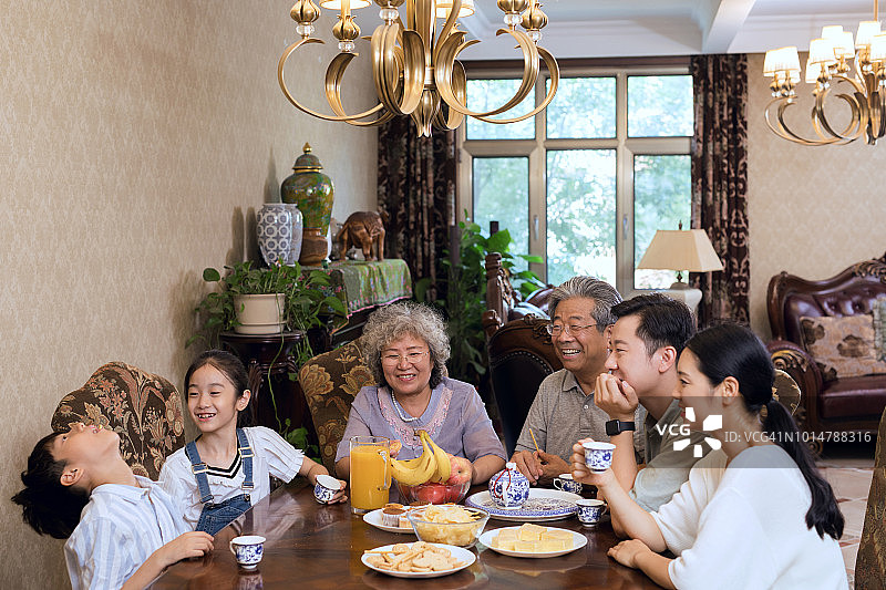 一个亚洲家庭在客厅一起享用下午茶。图片素材