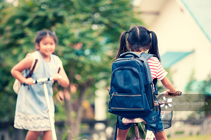 可爱的亚洲女孩背包骑自行车和她的姐姐骑滑板车去上学图片素材