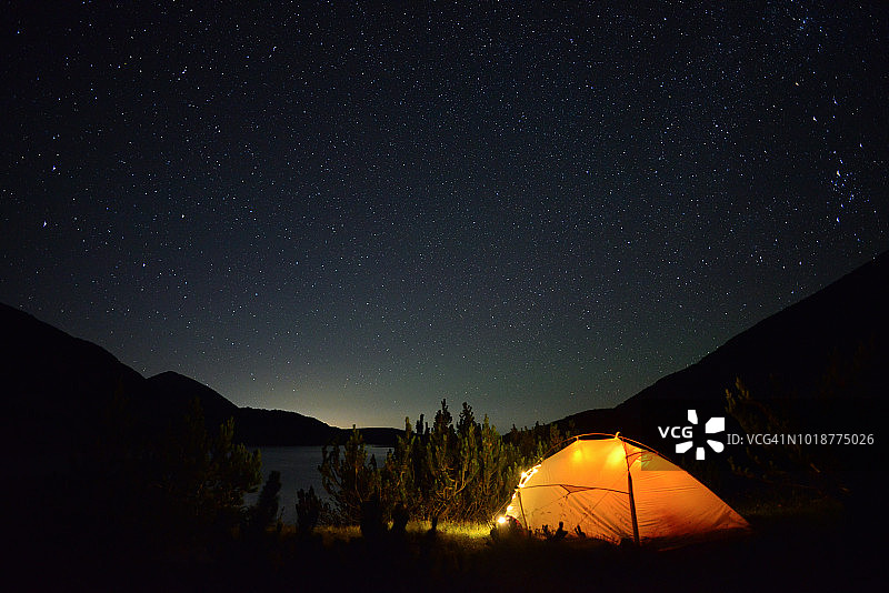 繁星满天，灯火通明的帐篷在山上图片素材