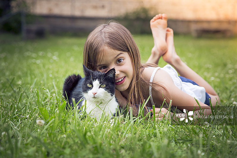 小女孩和猫躺在草地上的肖像图片素材