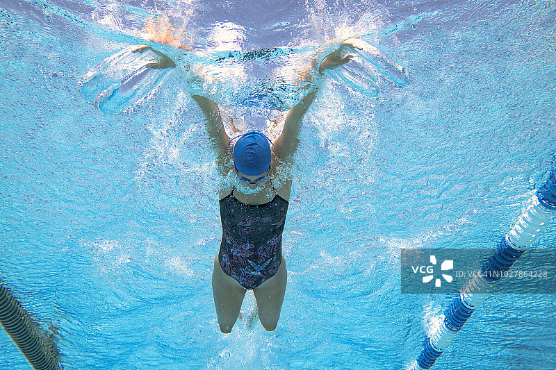 水下拍摄的年轻女子游泳蝶泳，上面的观点图片素材