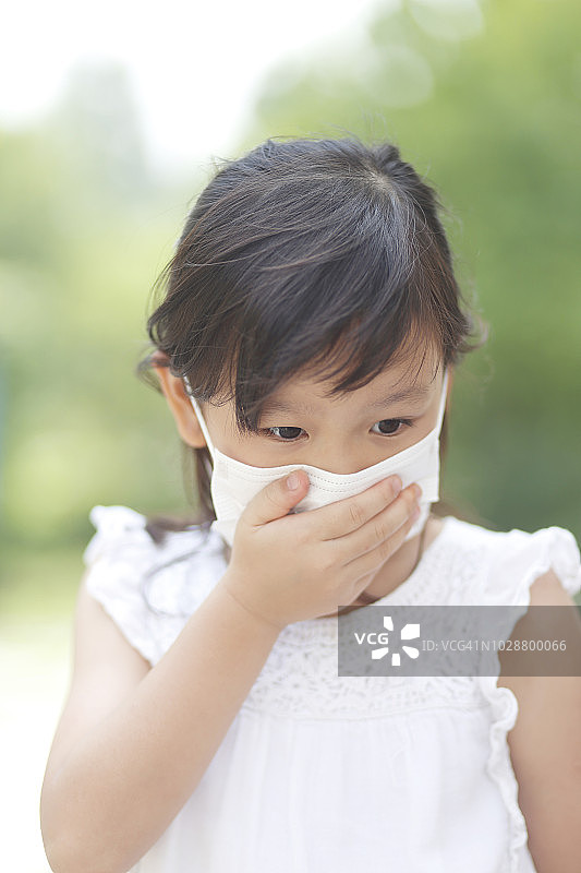 戴着流感口罩的小女孩在公园里图片素材