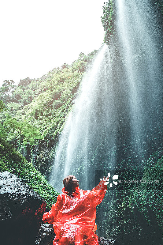 旅游女人冒险和站在Madakaripura瀑布放松，东爪哇岛，印度尼西亚图片素材