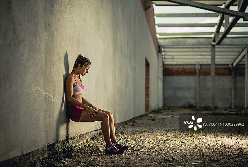 年轻的女运动员做墙坐运动训练。图片素材