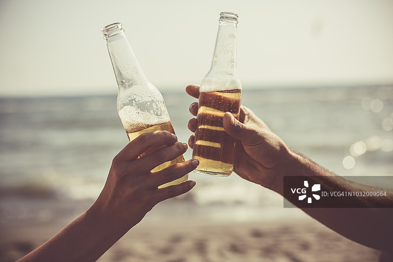 朋友们在海滩上拿着啤酒瓶敬酒图片素材