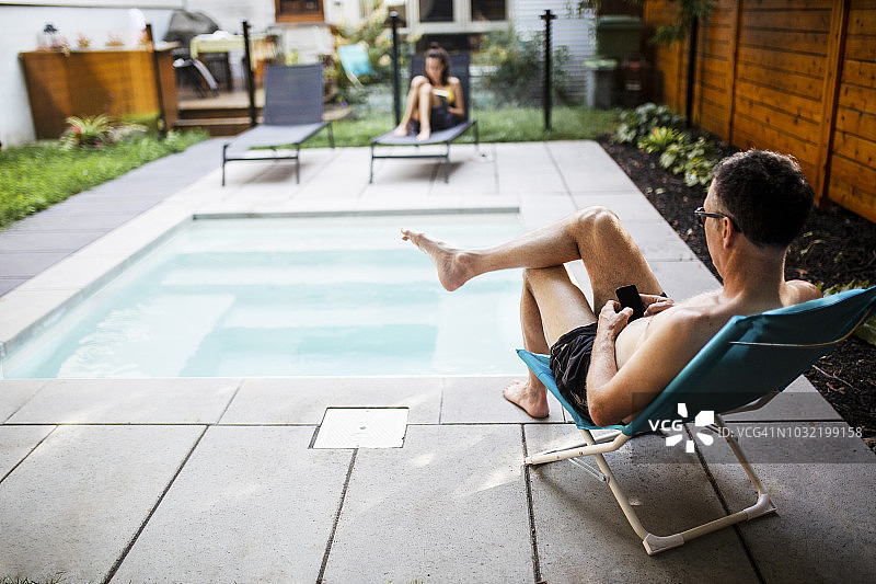 一个在游泳池边用手机的成熟男人图片素材
