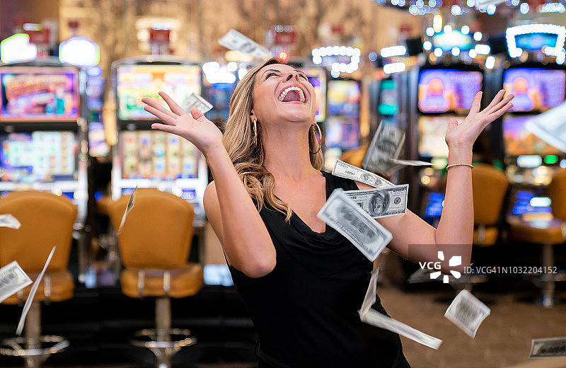 赌场里又漂亮又兴奋的女人兴奋地把赢来的钱抛向空中图片素材