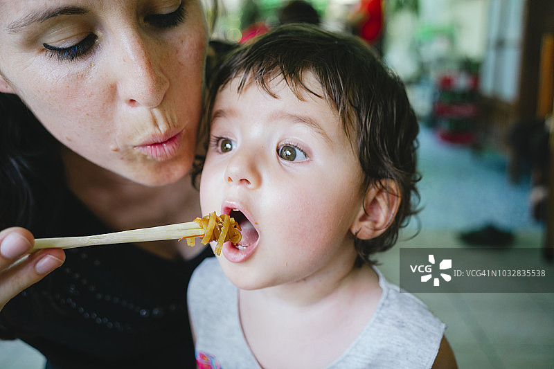 泰国，清迈，母亲用筷子给女儿吃泰式炒粉图片素材