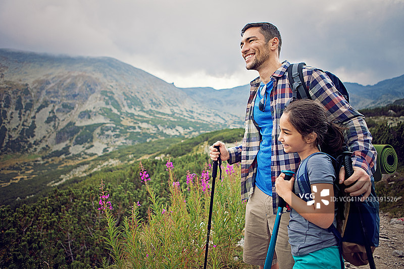 快乐的爸爸和女儿在山上徒步旅行，看风景图片素材