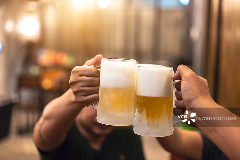 快乐的男性朋友在酒吧喝啤酒，碰杯图片素材