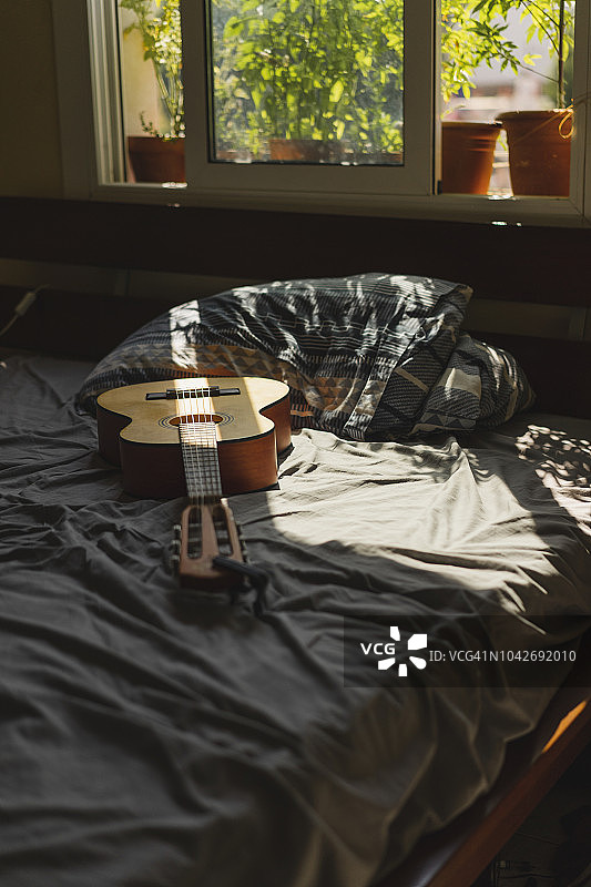 床上的原声吉他，阳光透过窗户照射进来图片素材