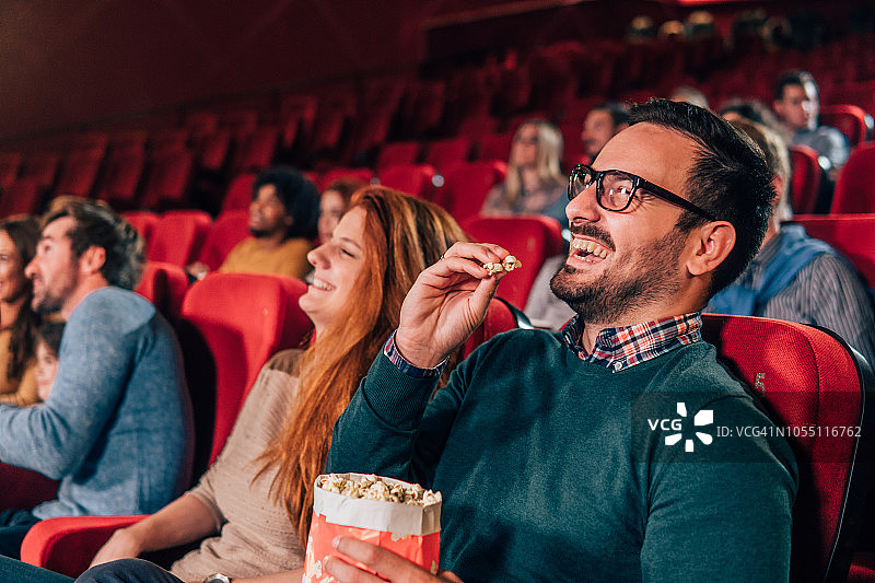 快乐的年轻人在电影院吃爆米花图片素材