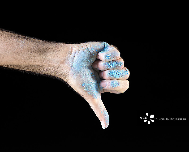 一个男人的手做拇指向下的手势，特写，手掌涂上白色在黑色的背景。图片素材