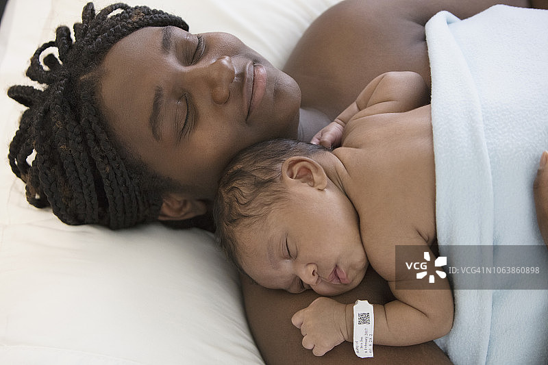 一位非裔美国妇女和她刚出生的婴儿睡在医院的病床上图片素材