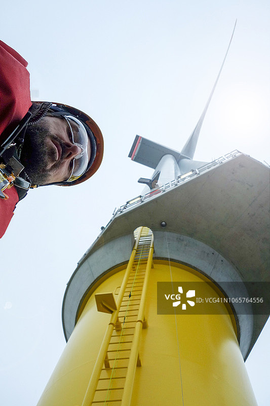 一名年轻的技术工人与巨型海上风力涡轮机自拍图片素材