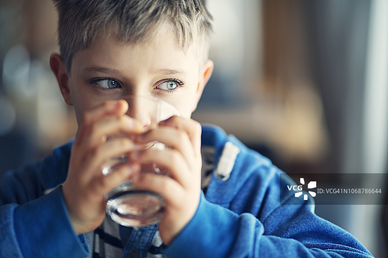 一个可爱的小男孩喝着一杯水图片素材