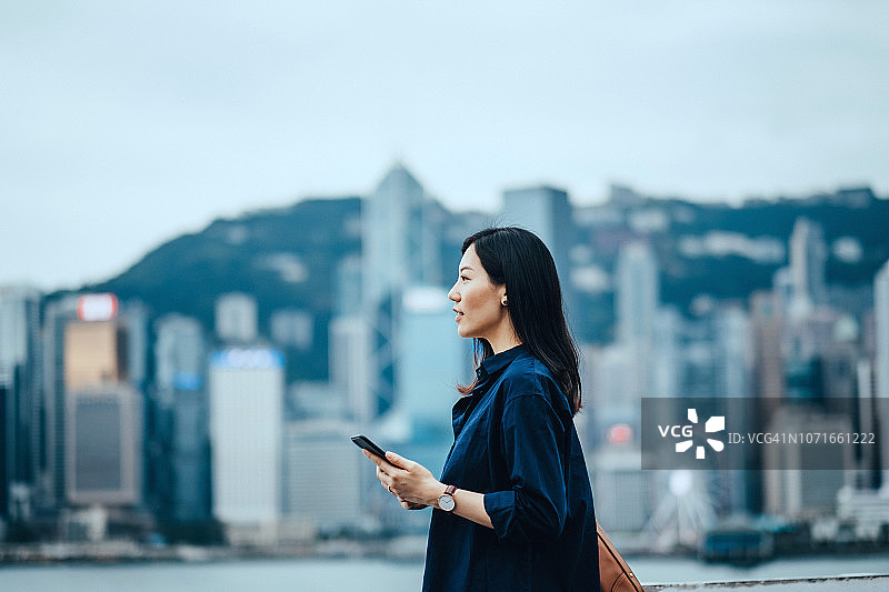 香港女商人使用智能手机对抗中央商务区图片素材