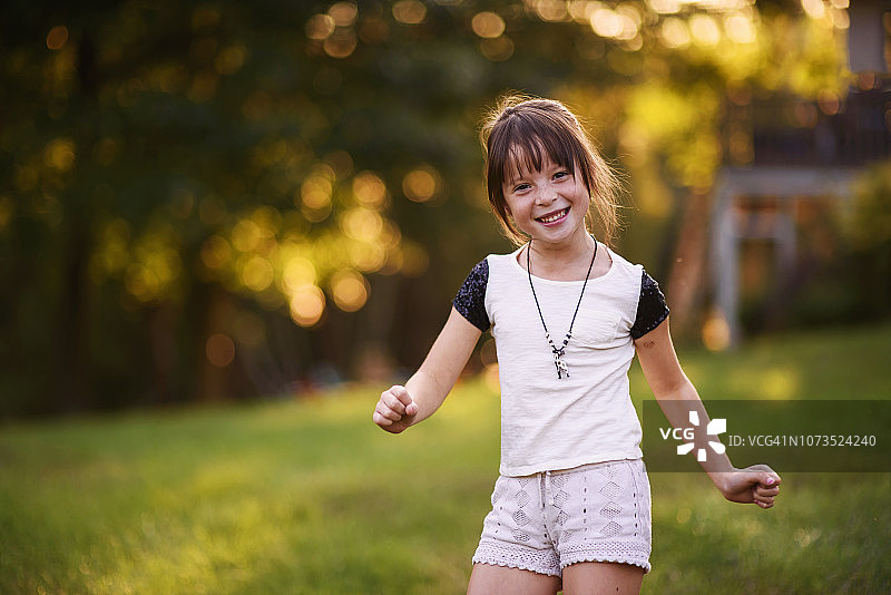 一个微笑的女孩在公园跳舞的肖像图片素材