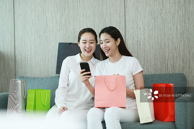 两个年轻女性用智能手机购物袋图片素材
