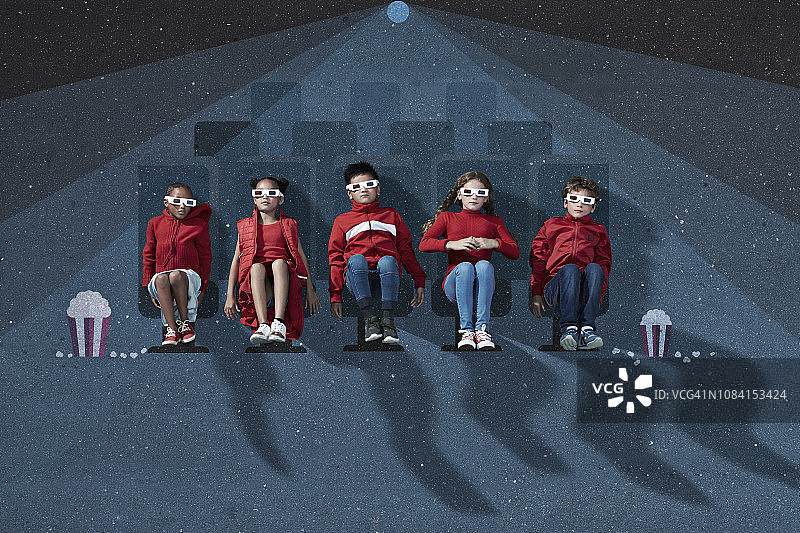 一群穿着红色衣服，戴着3d眼镜的孩子坐在虚构的电影院里图片素材